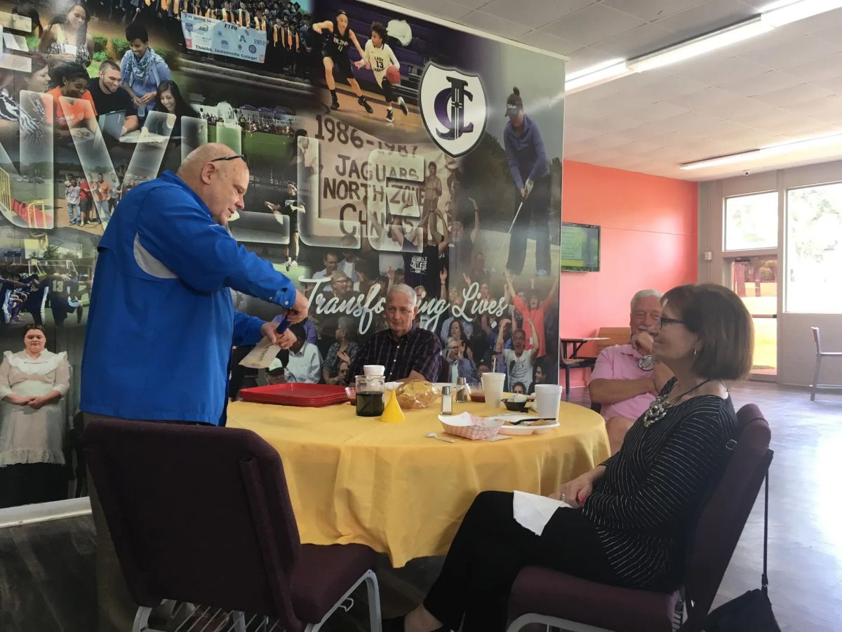 man in blue shirt at table with people